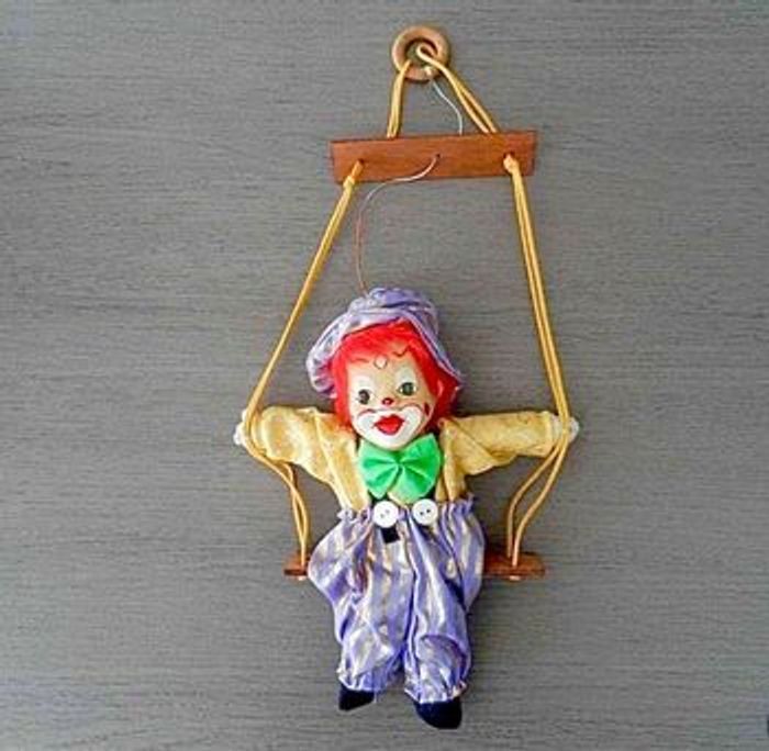 Clown tête porcelaine sur balançoire