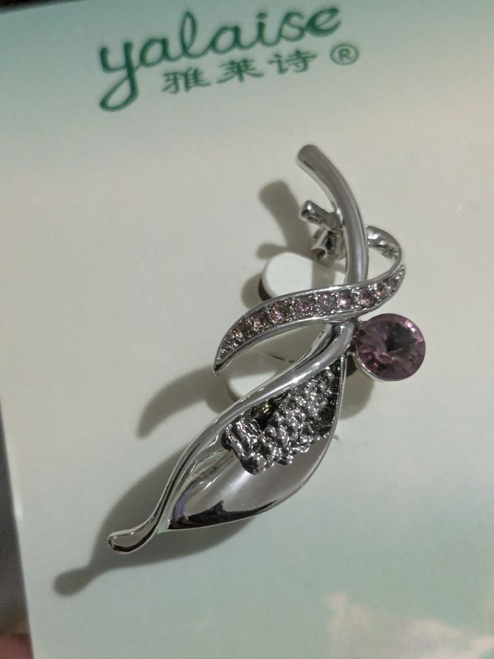 Belle broche métal argenté et strass.