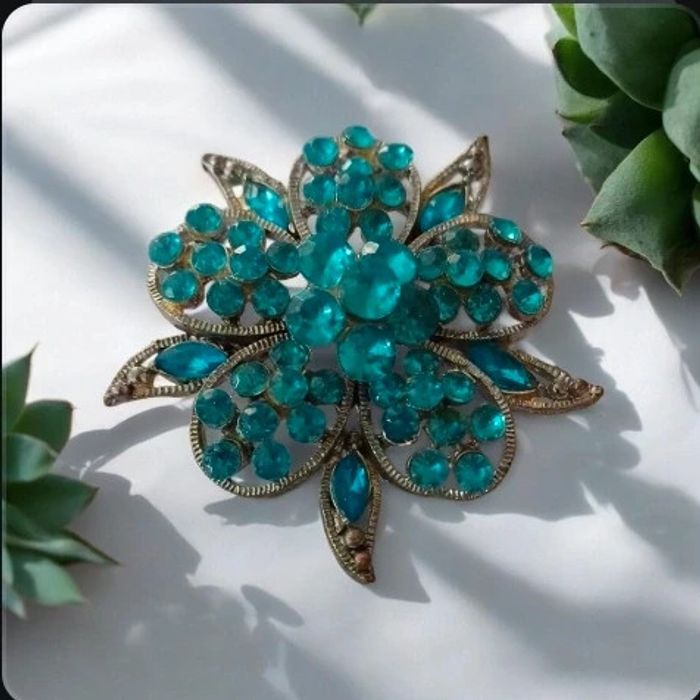 Broche en forme de fleur turquoise en strass. En très bon état.
