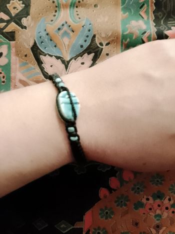 bracelet réglable en fil noir et perle bleu clair en céramique.