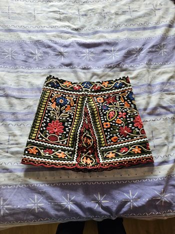 Jupe fond noire, fleur orange liseré bordeaux en bas.