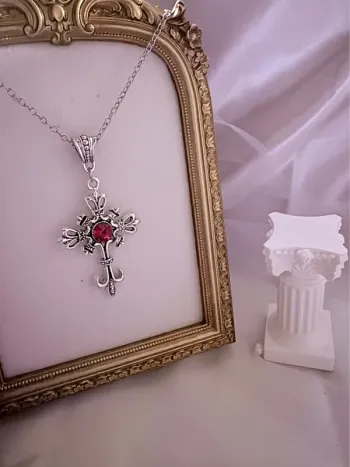 Collier chaîne avec bijoux croix et perle rouge sur le fermoir