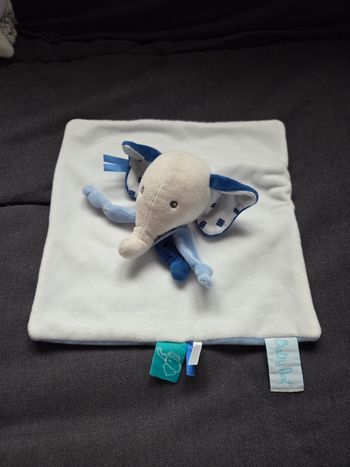 Doudou Éléphant Edgar carré plat blanc et bleu - Baby natDoudou carré plat en velours de couleur blanc et de l'autre côté en velours de couleur bleu. 
Éléphant Edgar sur le milieu du doudou. 
Intérieur des oreilles en tissu de couleur blanc avec petits tr