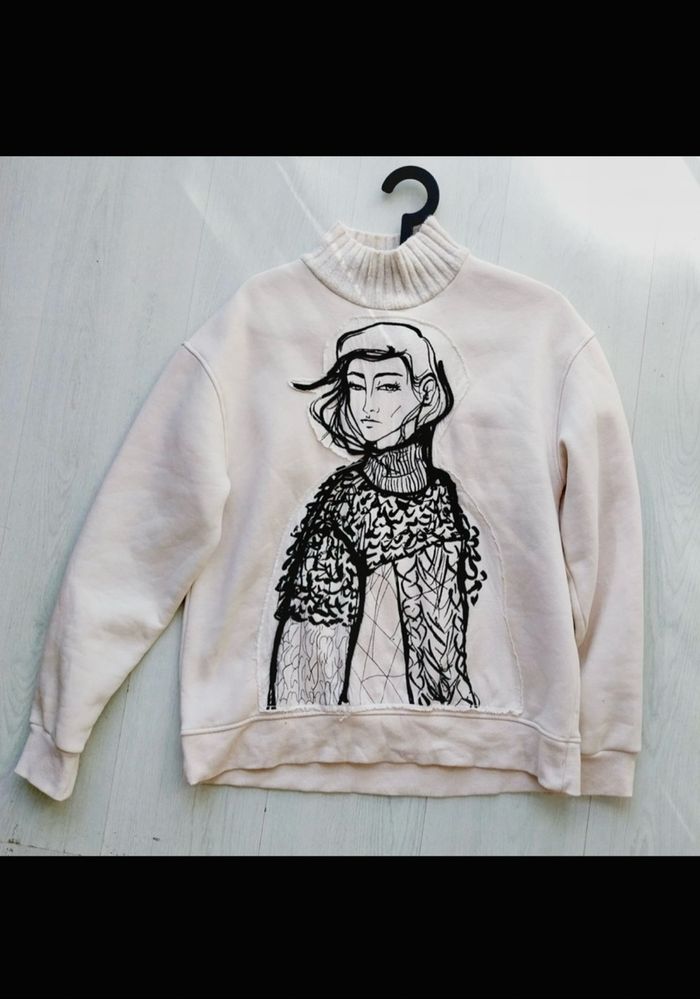 sweat Zara femme de couleur écru avec un imprimé visage et un col côtelé.