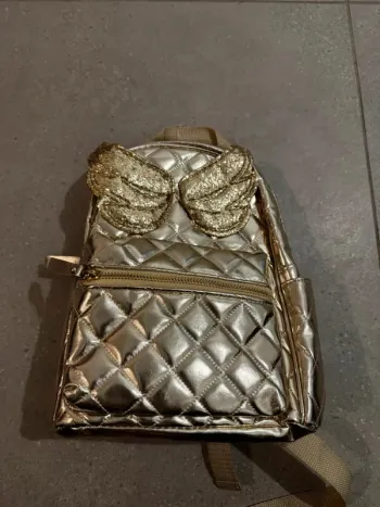 Petit sac à dos doré, bon état extérieur mais tâché à l'intérieur, 20x27cm
