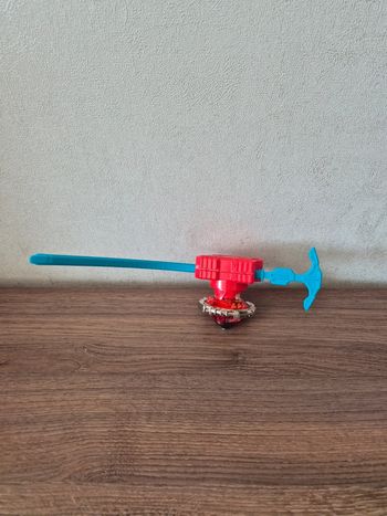 Lanceur Beyblade bleu et toupie rouge