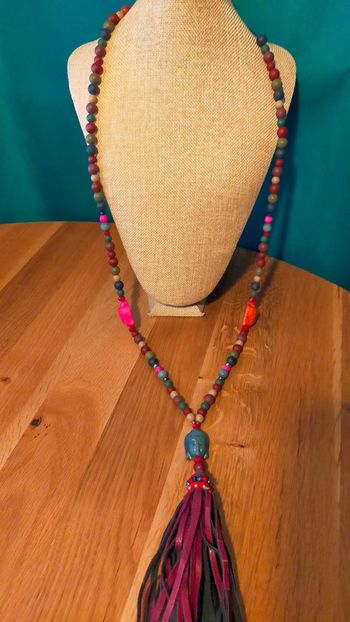 Collier long bohème ethnique – Têtes sculptées, perles mates et pompon cuir – Terres d’Ailleurs