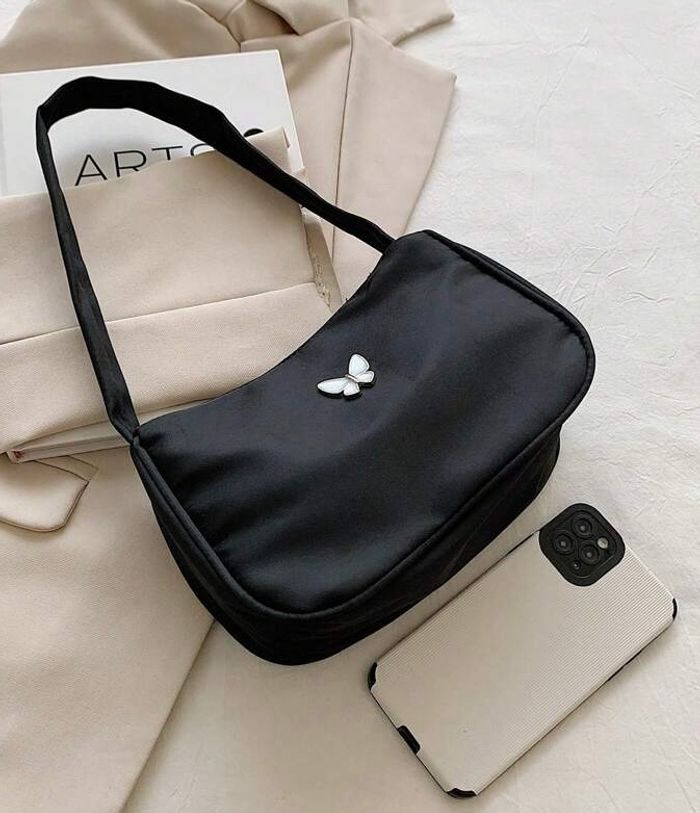 Sac à main noir avec un ornement papillon blanc
