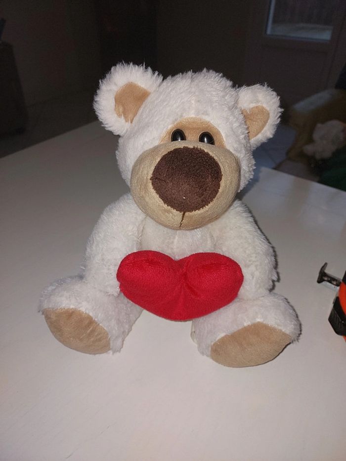 Peluche nounours tenant un cœur rouge